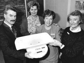 January 1991. Ian Cole presents baby scales to health visitors at Wickford Health Centre. | Echo newspaper.