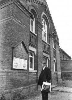 The Congregational Church became Christ Church in 1970. This photograph was taken a short while before the church was demolished to make way for shop and office development. It shows Mr Ivan Pickman reading the notices which advised visitors to use Wesley Hall, in Southend Road, or St. Andrews, in London Road.