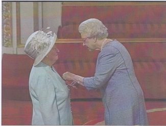 Audrey being presented with the MBE by the Queen