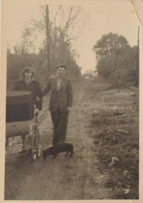 Walking along Belmont Avenue in 1958. Daphne and Peter White with their dachshund, Mandy. Nicholas is in the pram. 